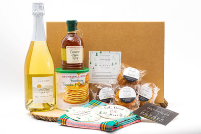 Holiday themed brunch gift containing sparkling brut, pancake mix, cinnamon apple syrup, assorted muffins, holiday tea towel and coasters