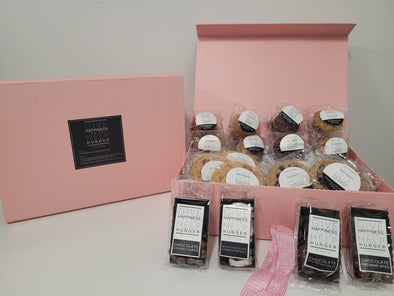 Pink box packed with assorted muffins, cookies and chocolate-covered raisins, chocolate-covered malt balls, chocolate-covered brownie bites & white chocolate-covered pretzels